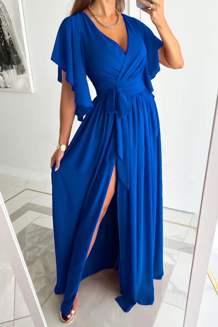 Modell steht in einem blauen Maxikleid mit Schlitz vorne