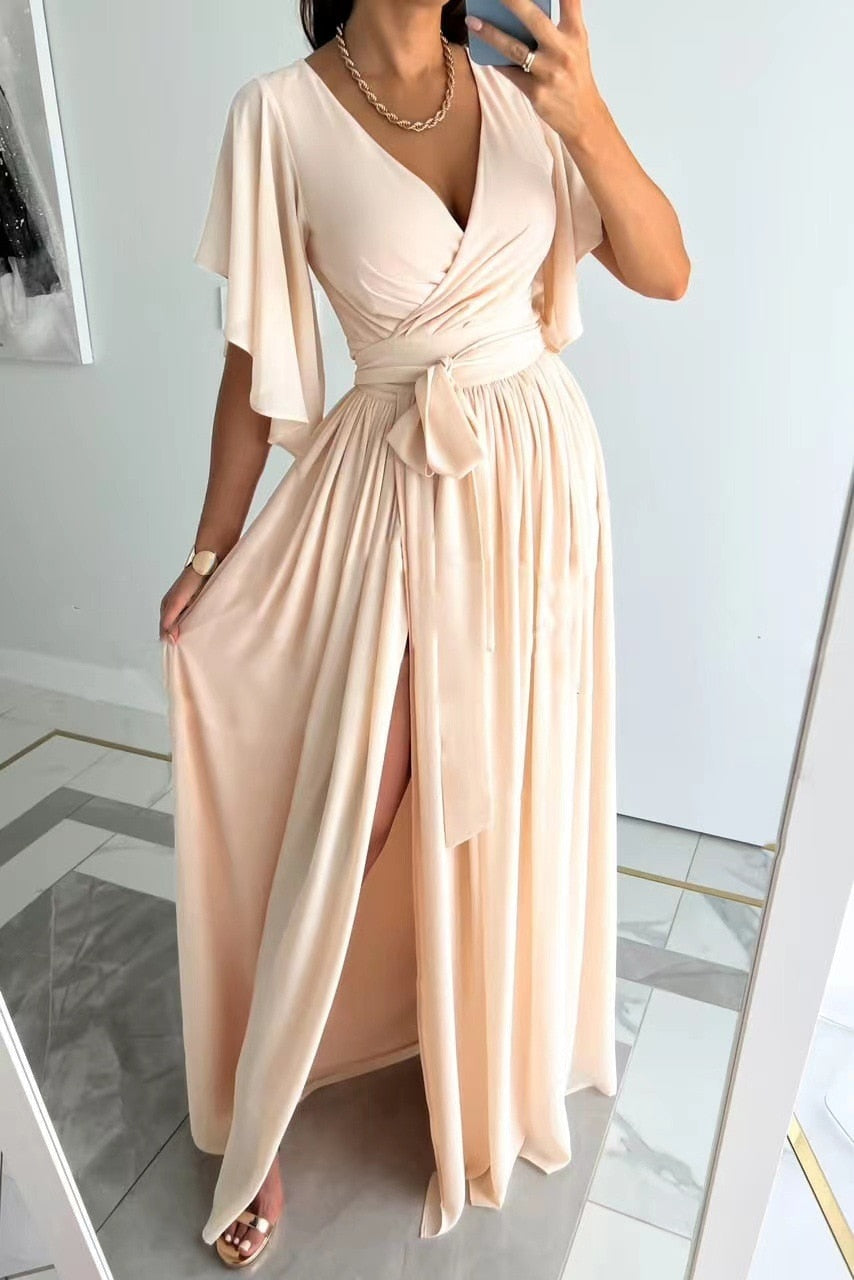 "Modell steht in einem beigen Maxikleid mit Schlitz vorne."