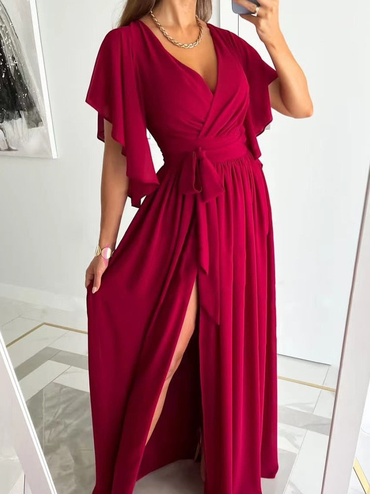 Modell steht mit rotem Maxikleid mit Schlitz vorne.