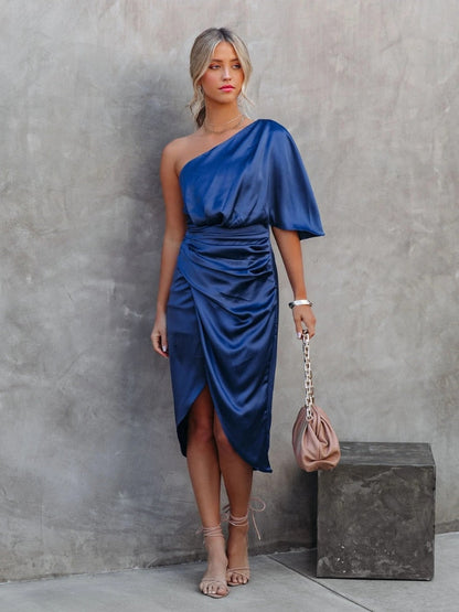 Ein Model steht in einem blauen Satin-One-Shoulder-Kleid vorne
