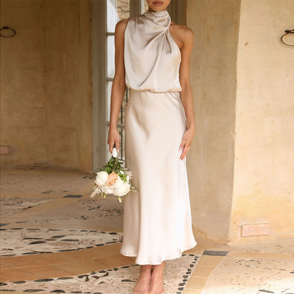 Modell steht mit beiger One-Shoulder Satin-Kleid, Vorderansicht.